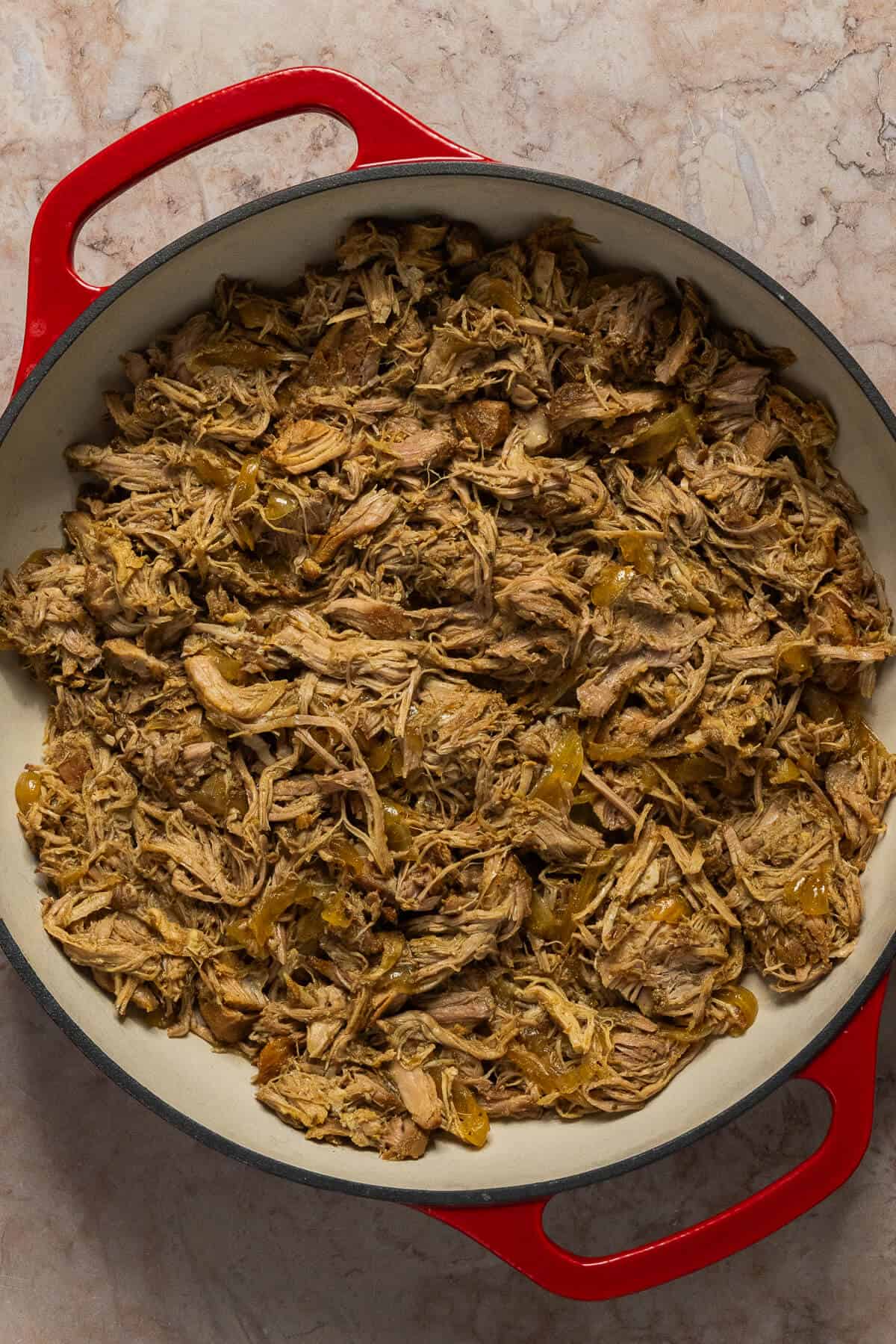 The finished shredded slow cooker carnitas in a large pot.