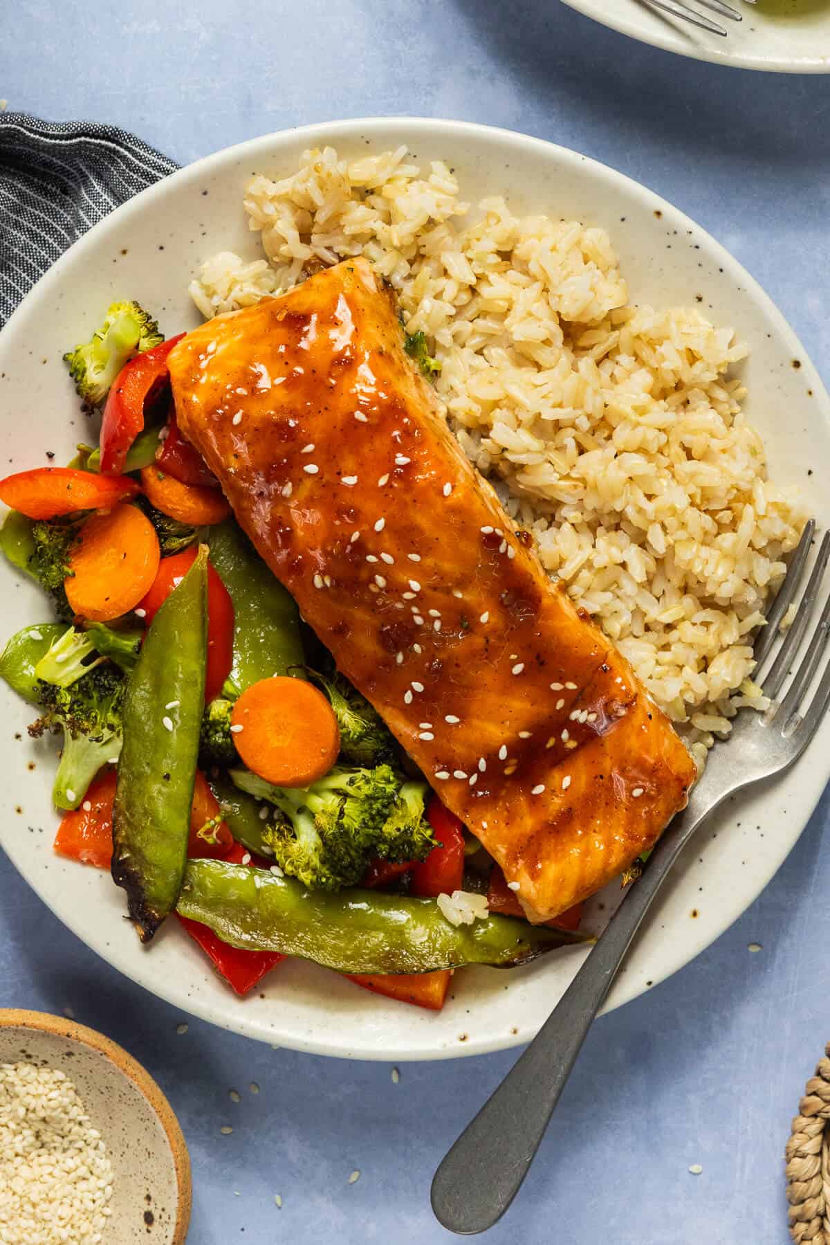 A plate with brown rice, teriyaki salmon, and roasted vegetables.