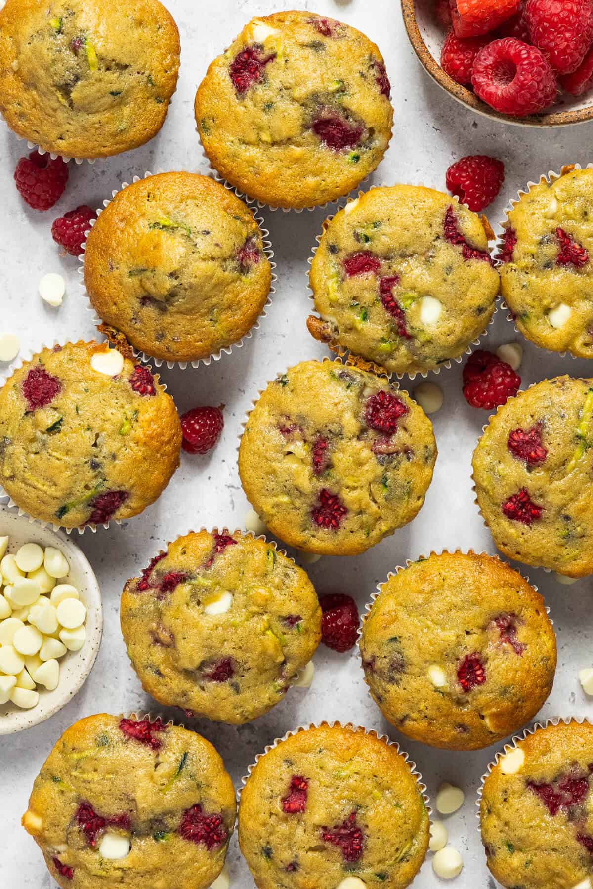 Thirteen white chocolate raspberry zucchini muffins.