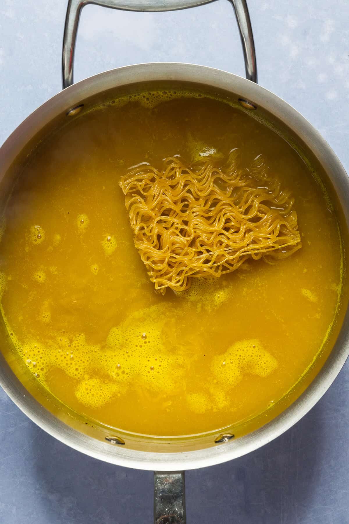 Pan with ramen noodles being added.