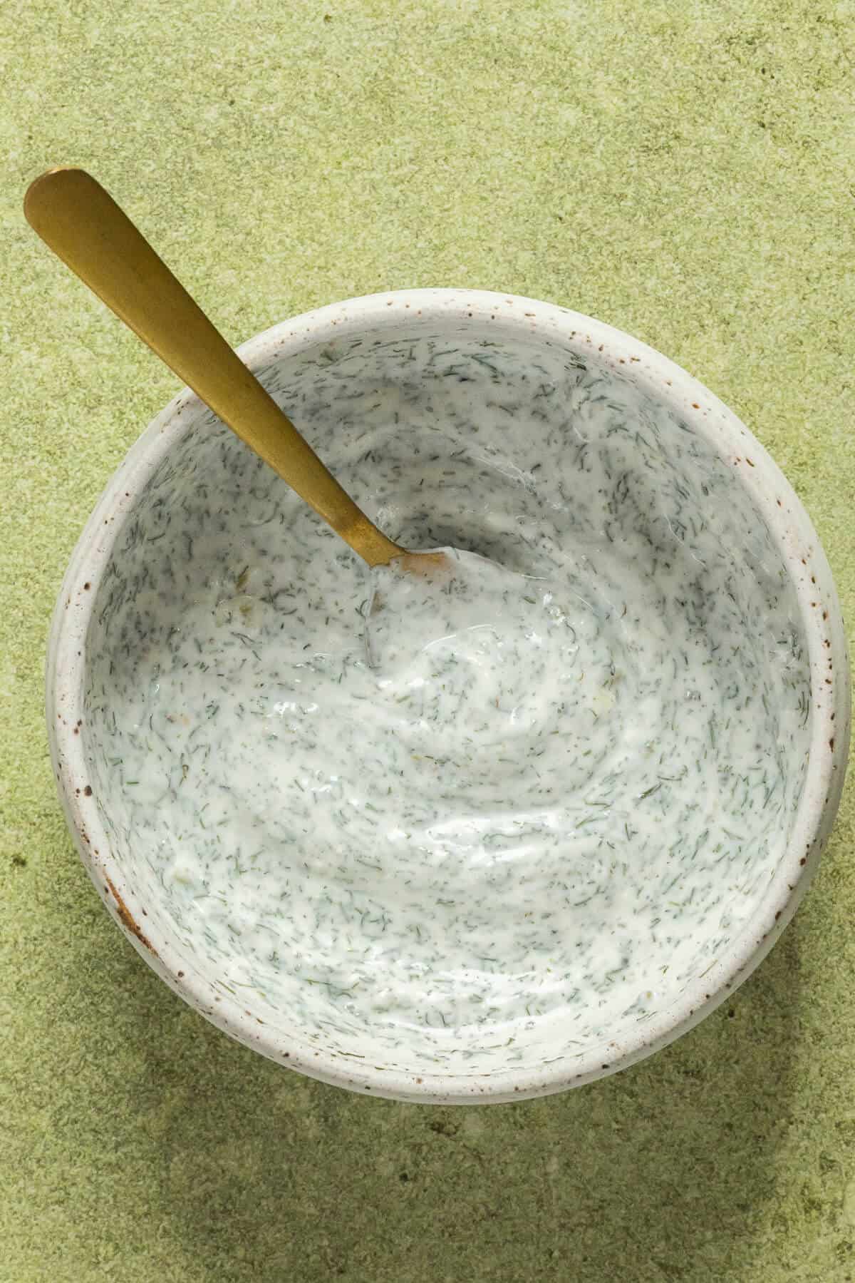 A small mixing bowl with the yogurt dill sauce.