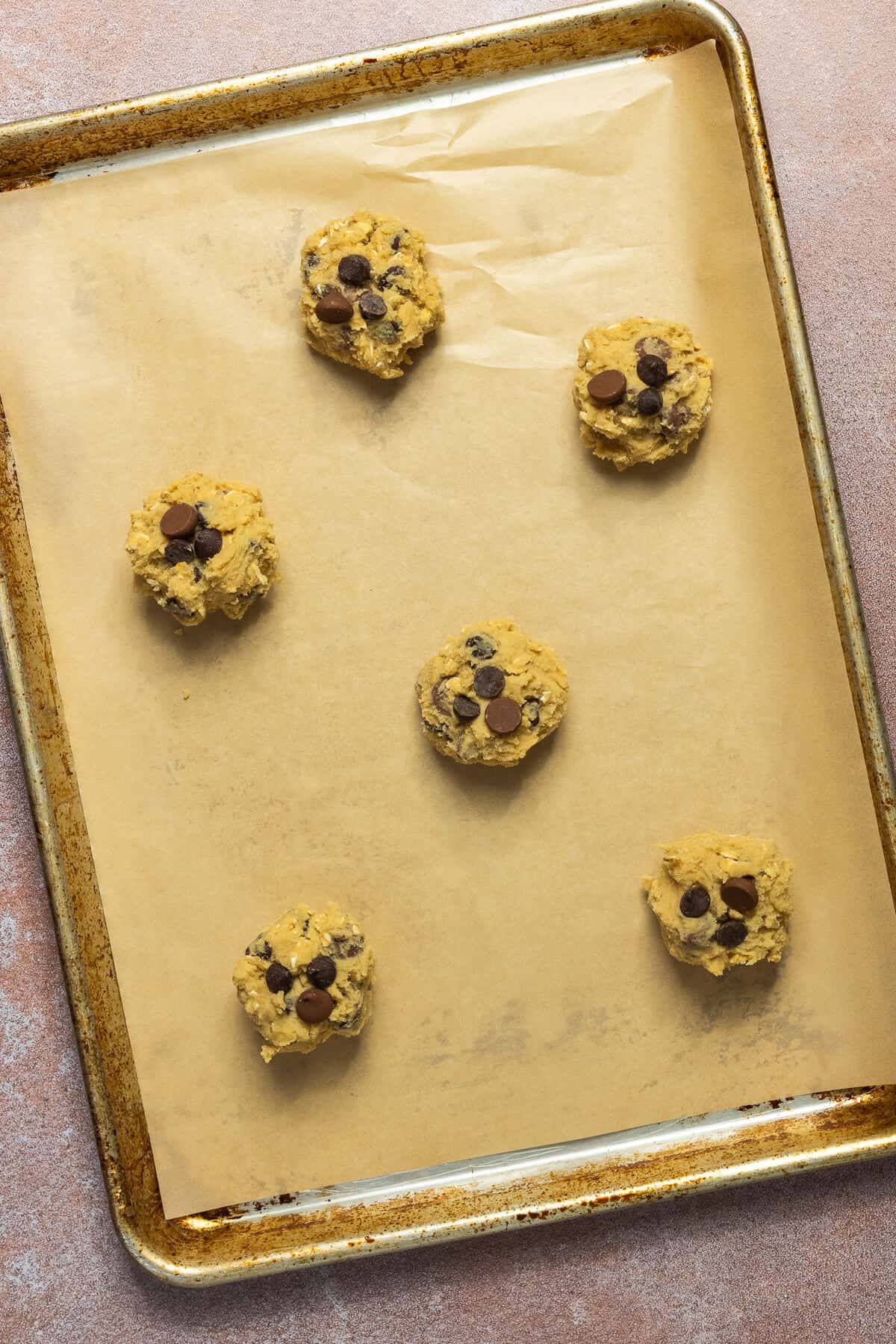 A baking sheet with 6 oatmeal chocolate chip cookie dough balls.