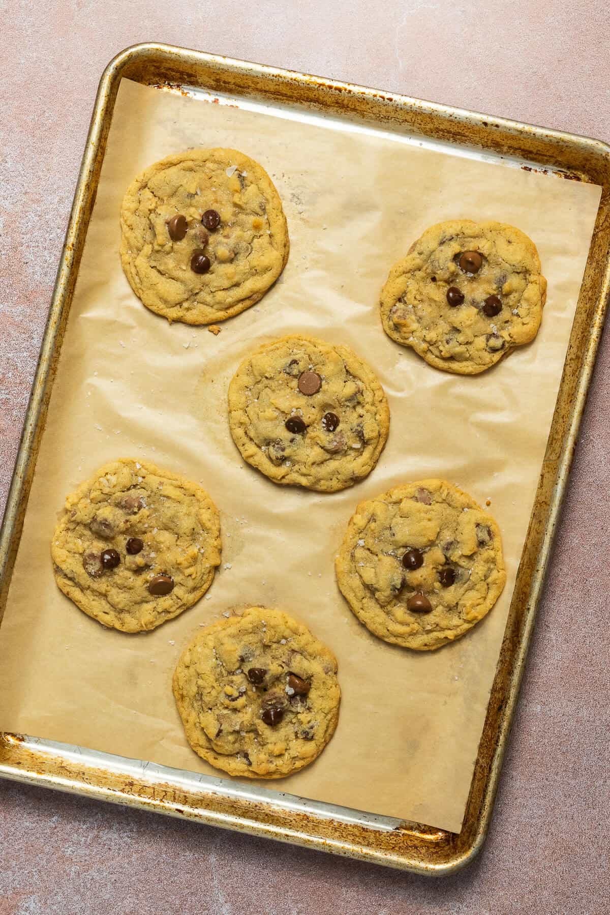 A baking sheet with 6 baked oatmeal chocolate chip cookies.