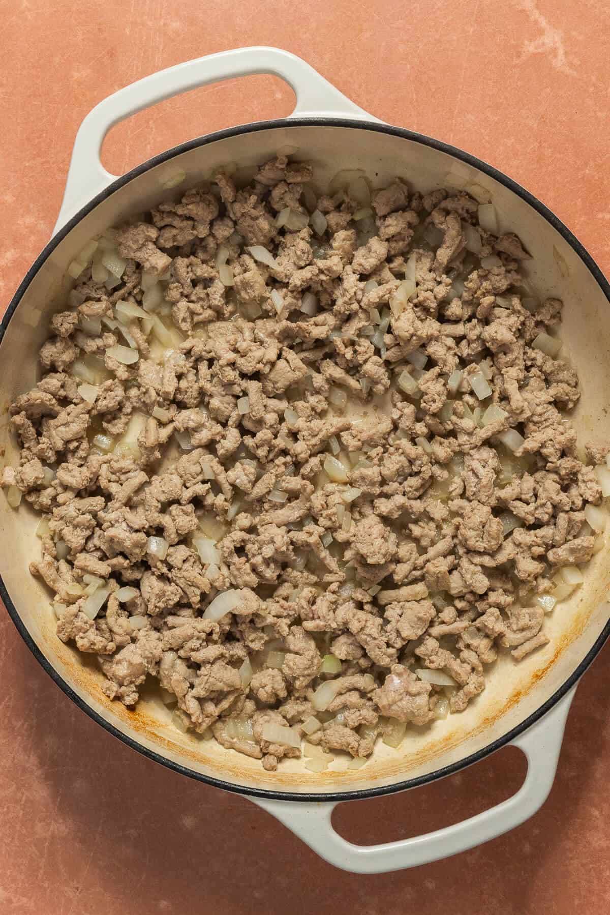 A skillet with cooked onion and chicken sausage.
