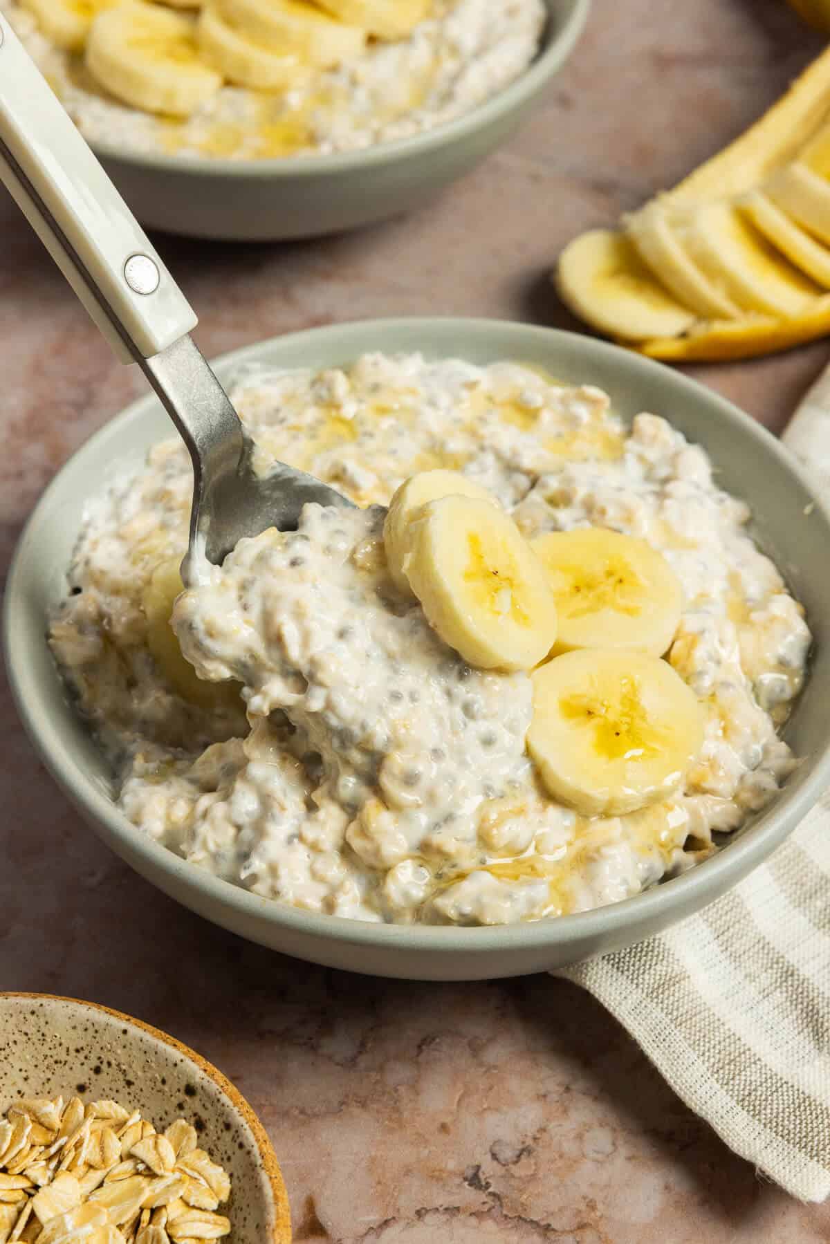 A spoonful being scooped out of a bowl of banana overnight oats.