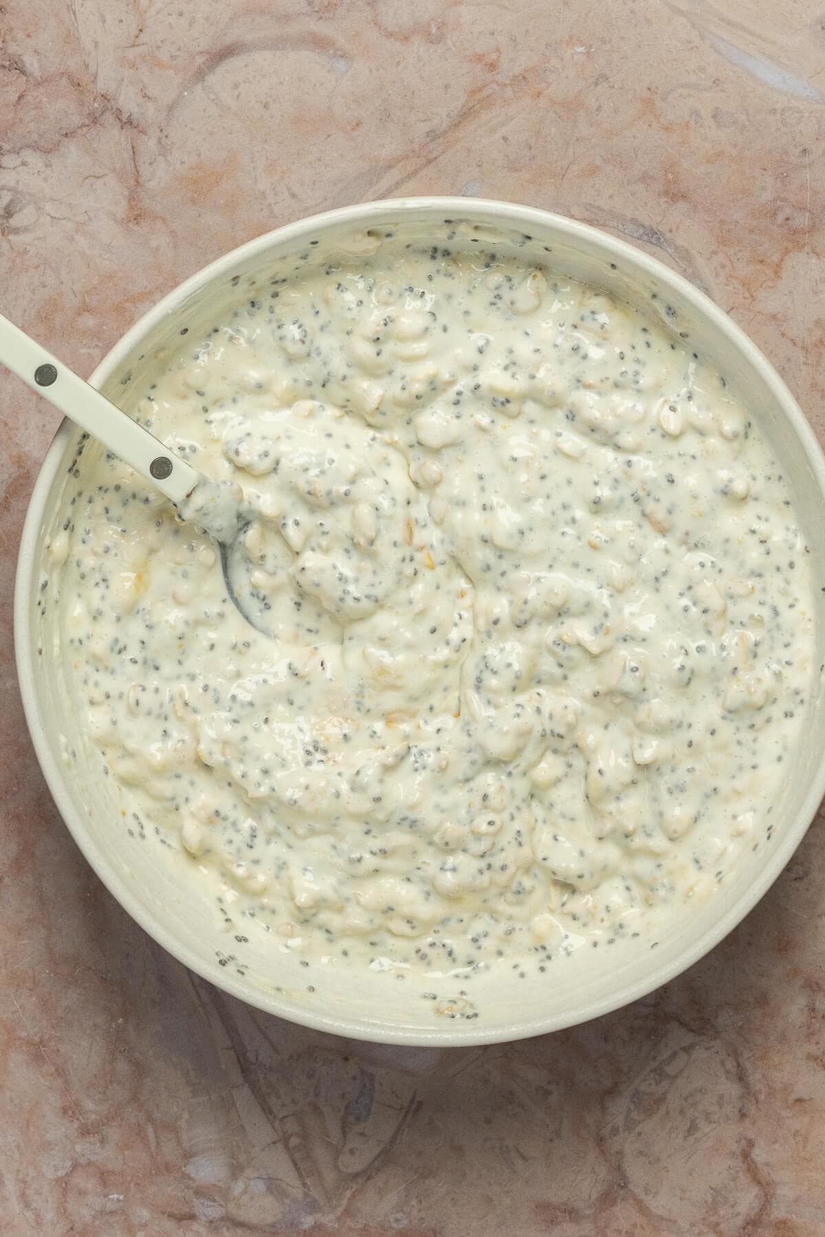 A large mixing bowl with chia seeds mixed into the banana cream pie overnight oats.