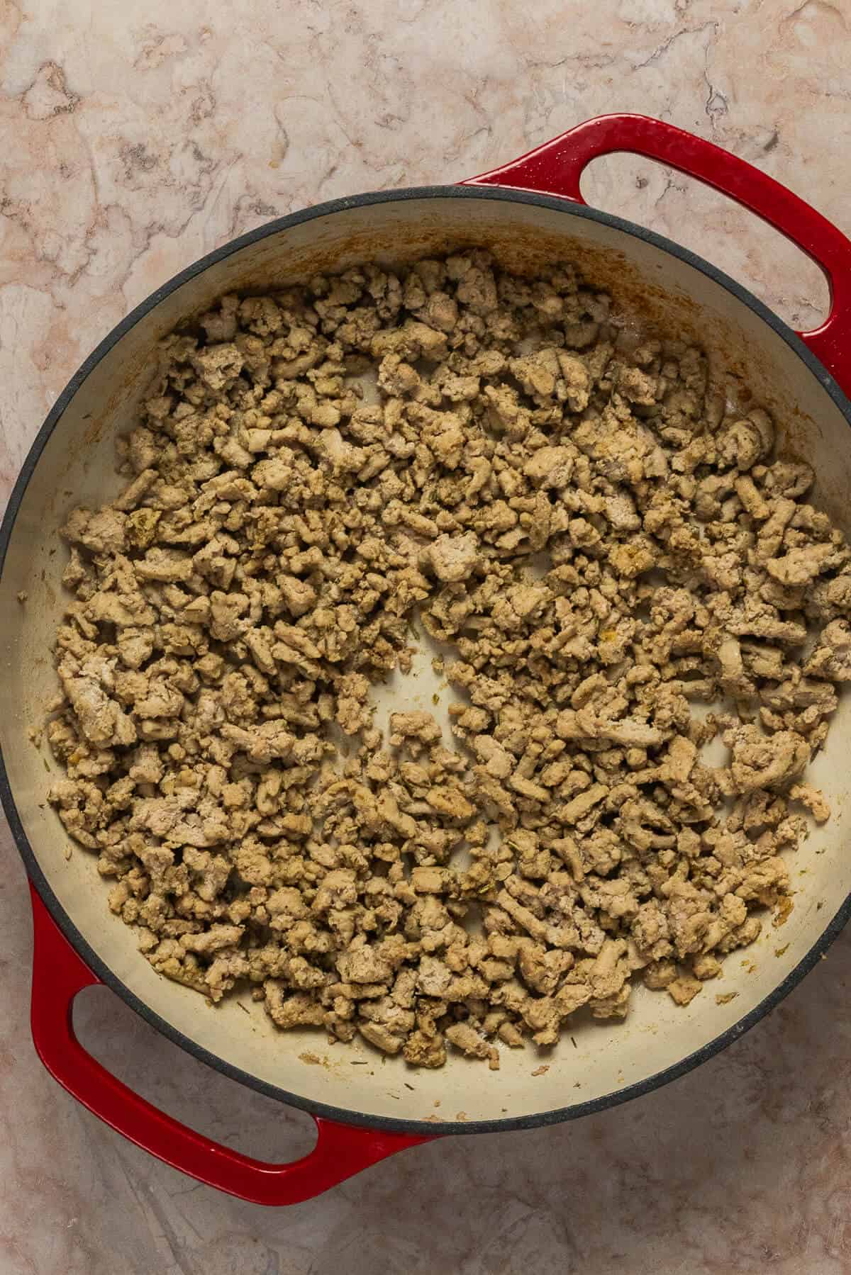 A large skillet with cooked ground meat.