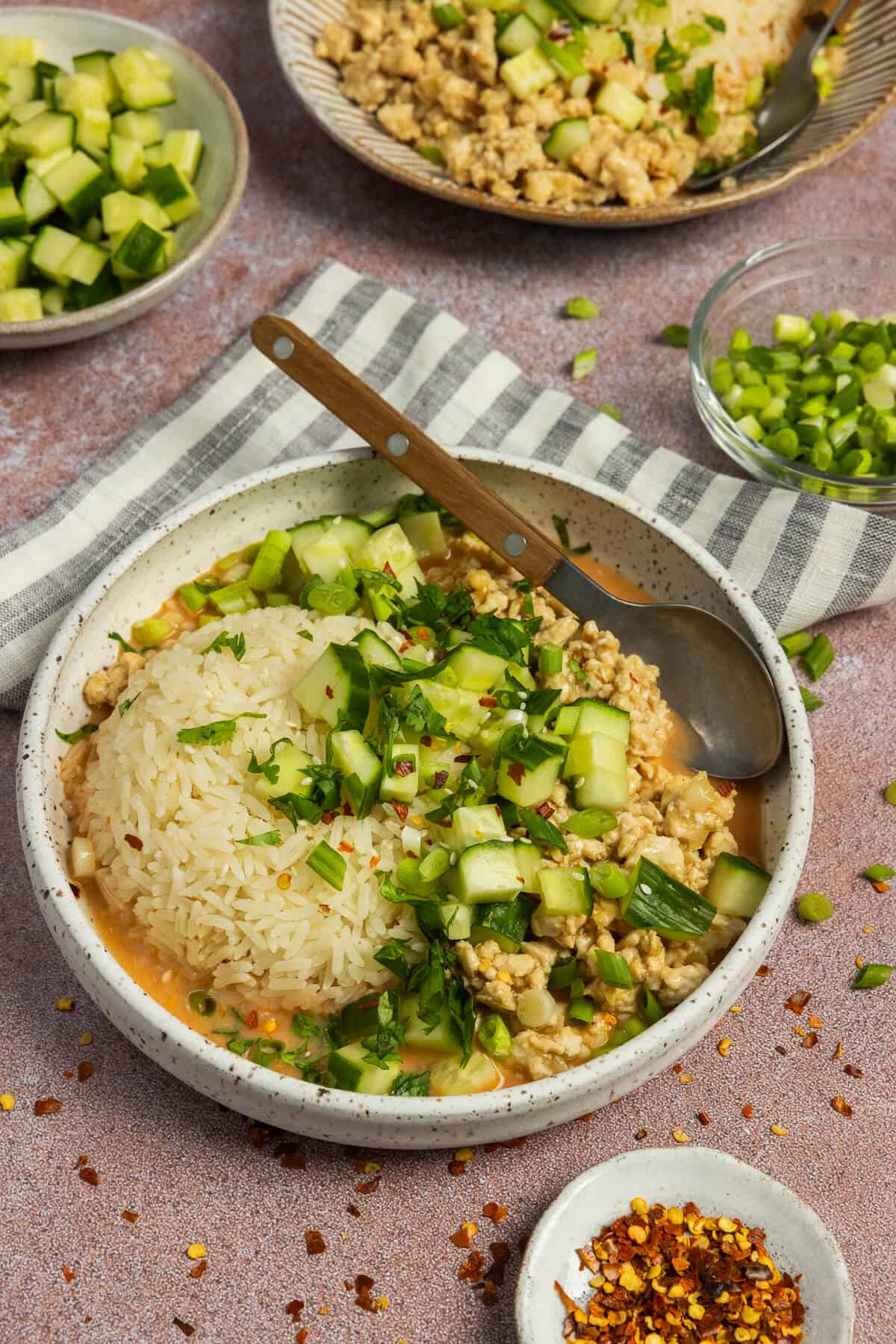 A finished curry bowl garnished with chopped cucumber, green onion, cilantro and red pepper flakes.