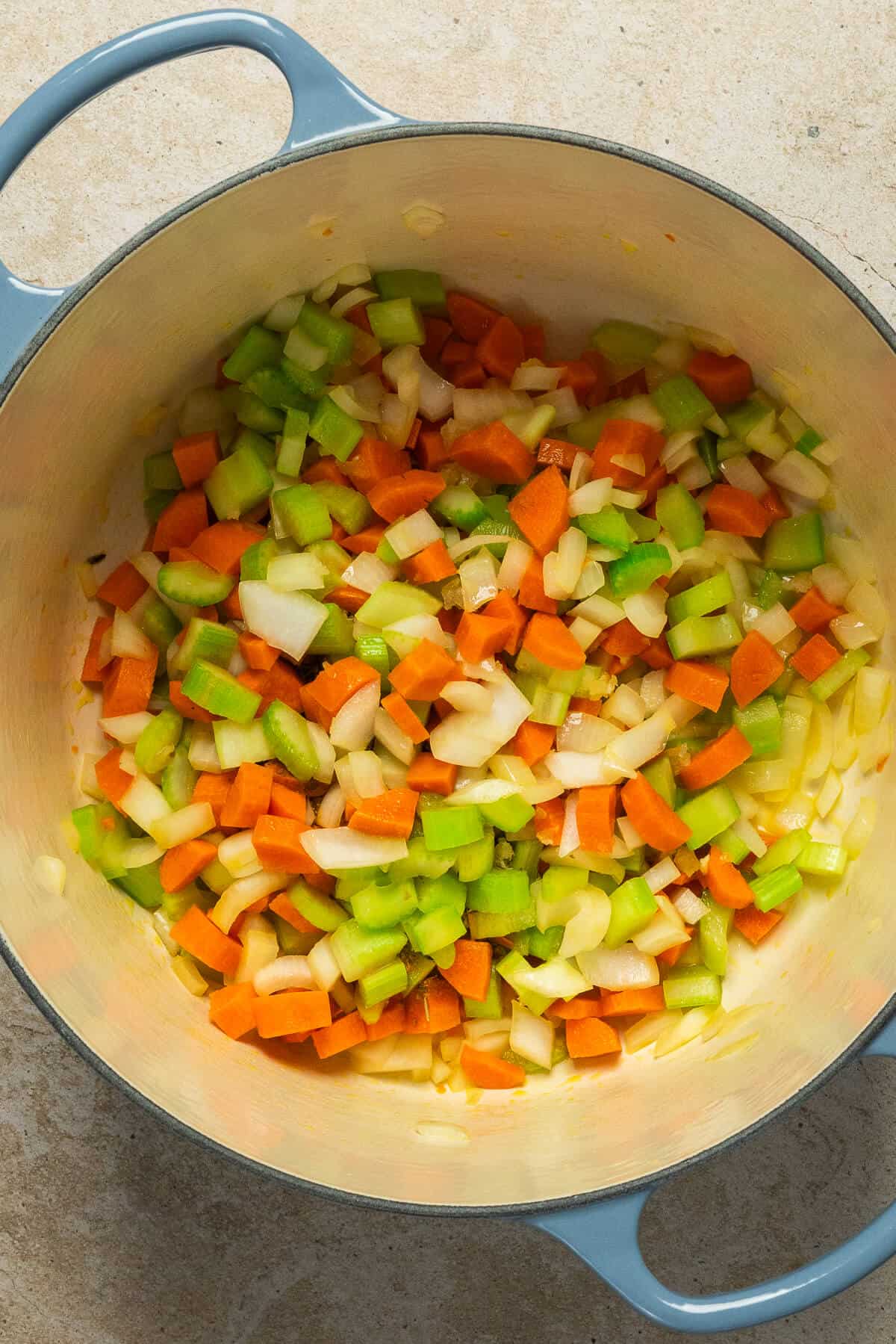 A large pot with diced onion, carrot, and celery.