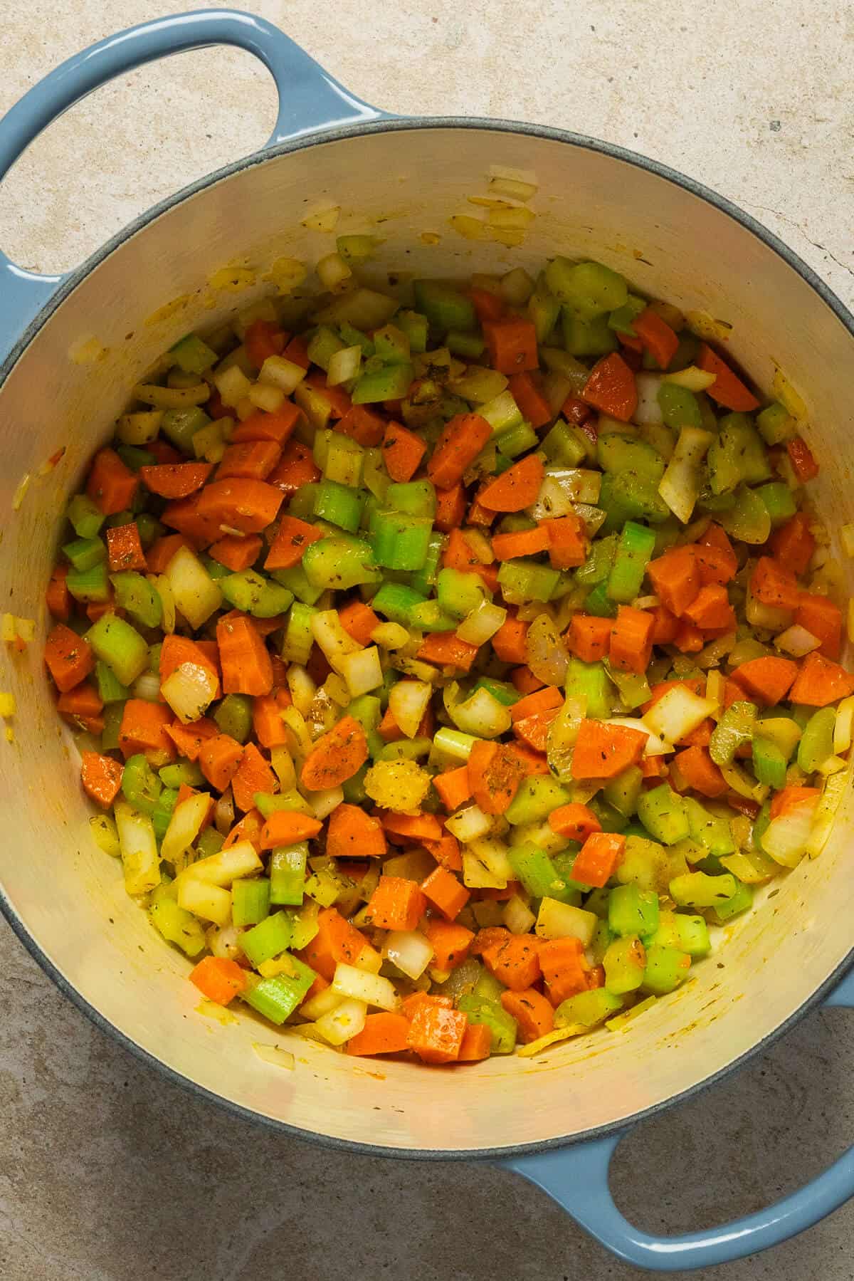 A large pot with diced vegetables mixed with the chicken noodle soup seasonings.