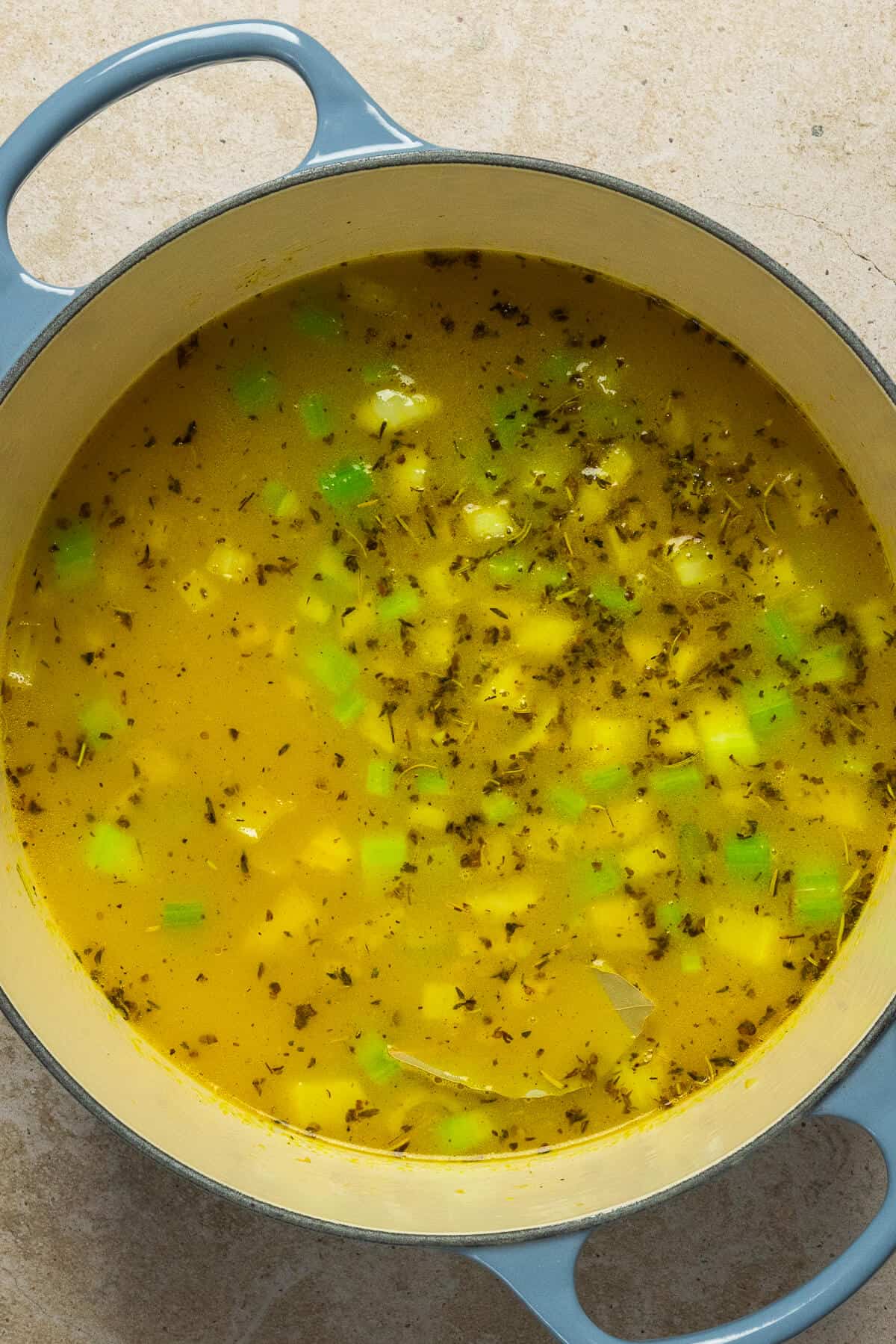 A large pot with chicken broth added to the diced vegetables and chicken noodle soup seasoning.