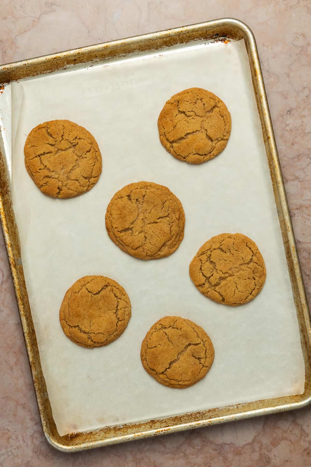 A baking sheet with six baked pumpkin spice snickerdoodle cookies.
