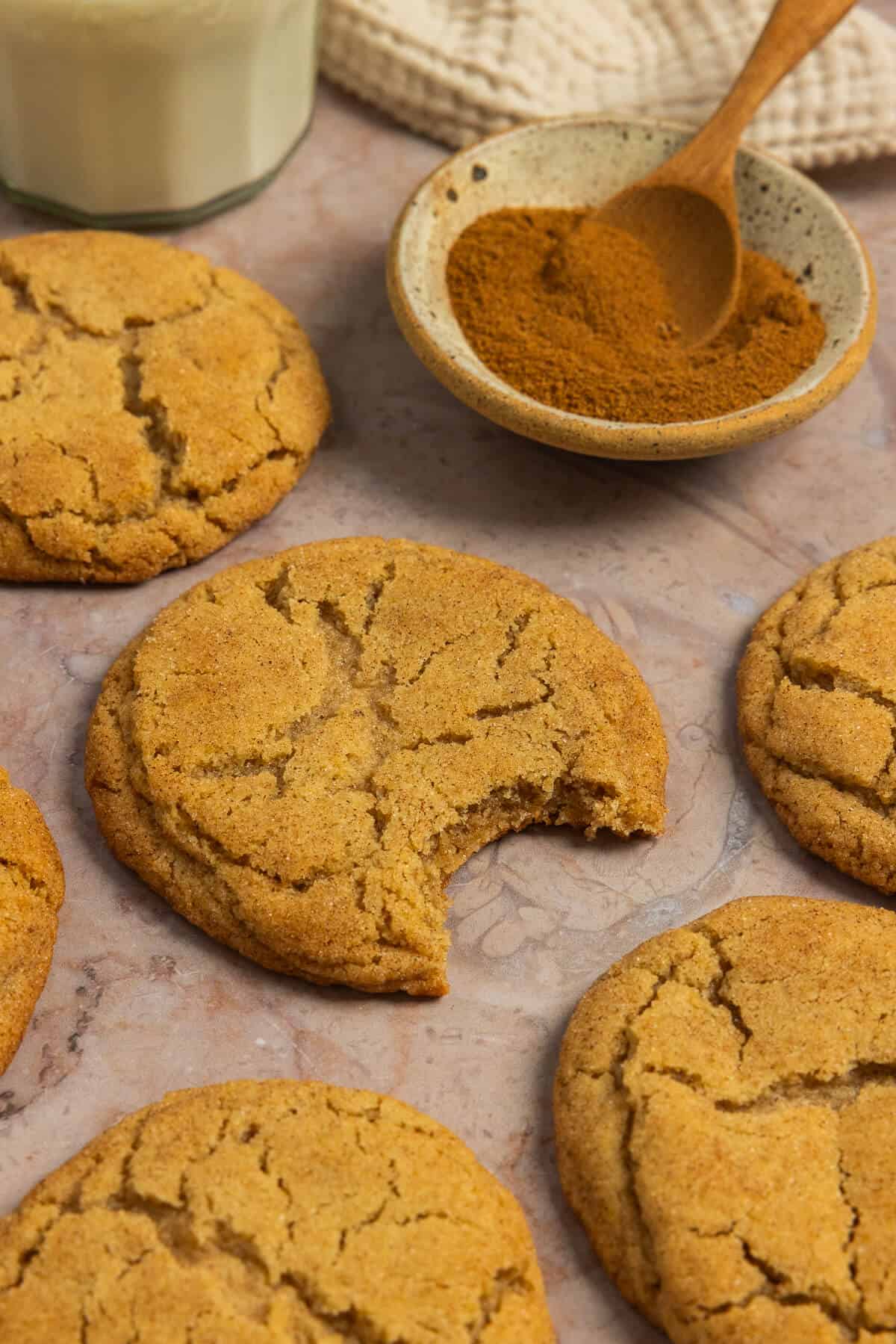 Pumpkin spice snickerdoodles spread out with one with a bite taken out of it.
