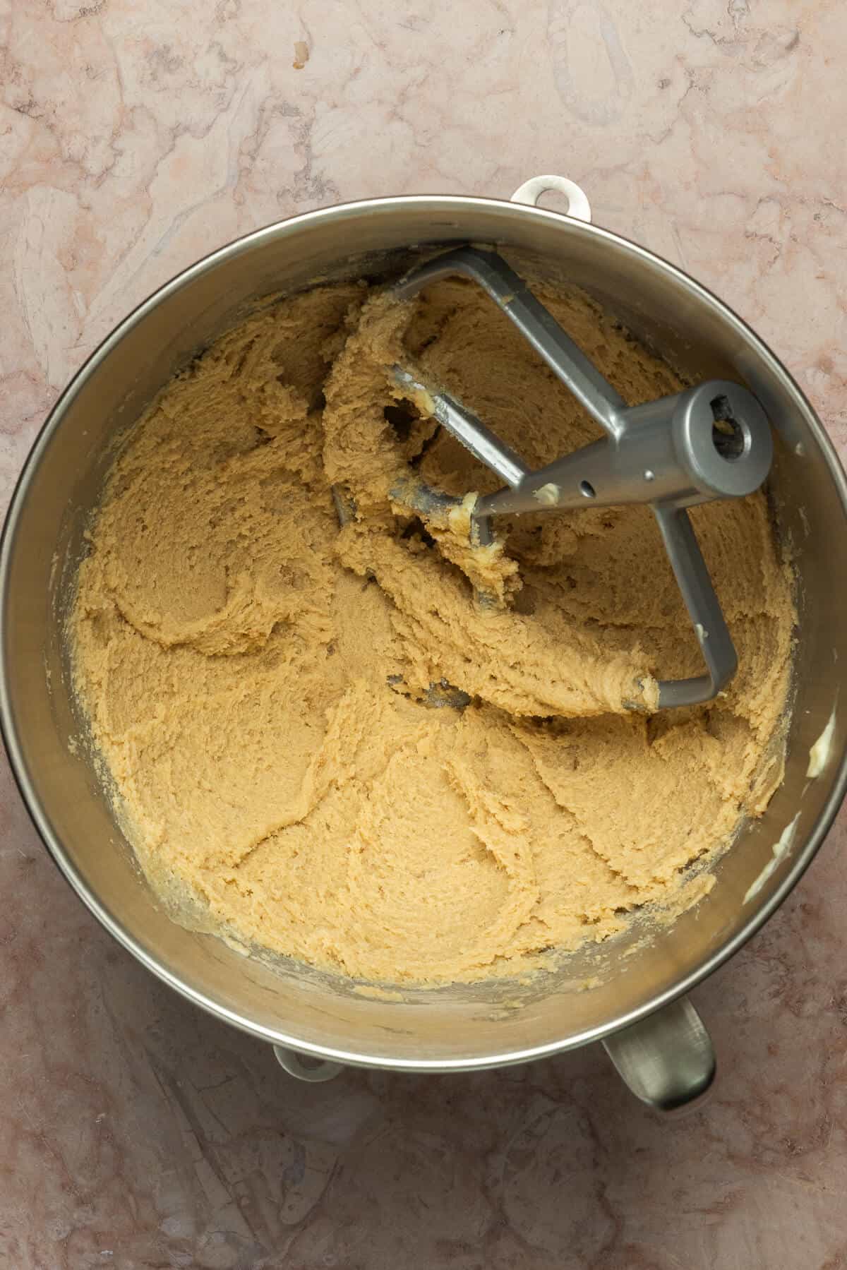 A Kitchenaid mixing bowl and paddle mixer with creamed butter and sugar.