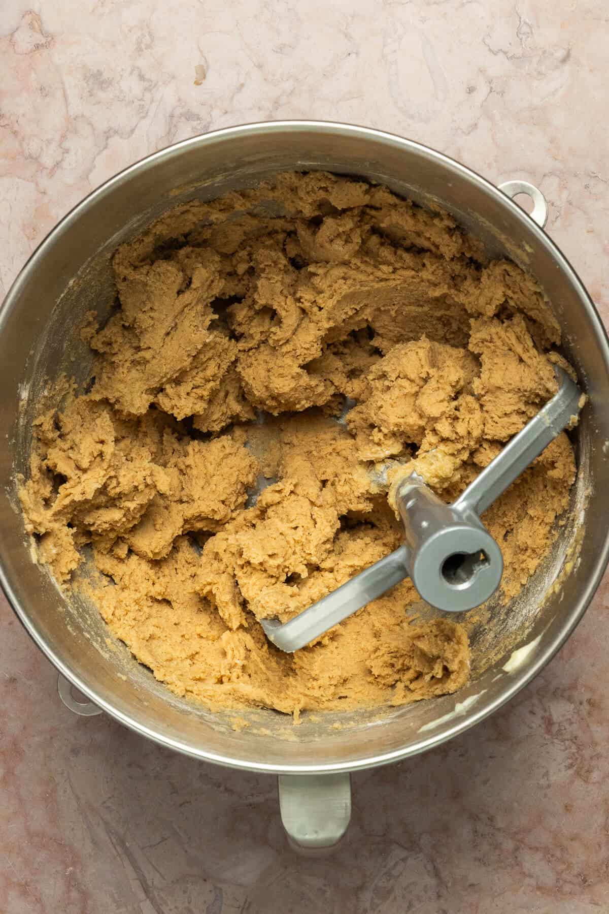 A Kitchenaid mixing bowl and paddle mixer with mixed snickerdoodle cookie dough.