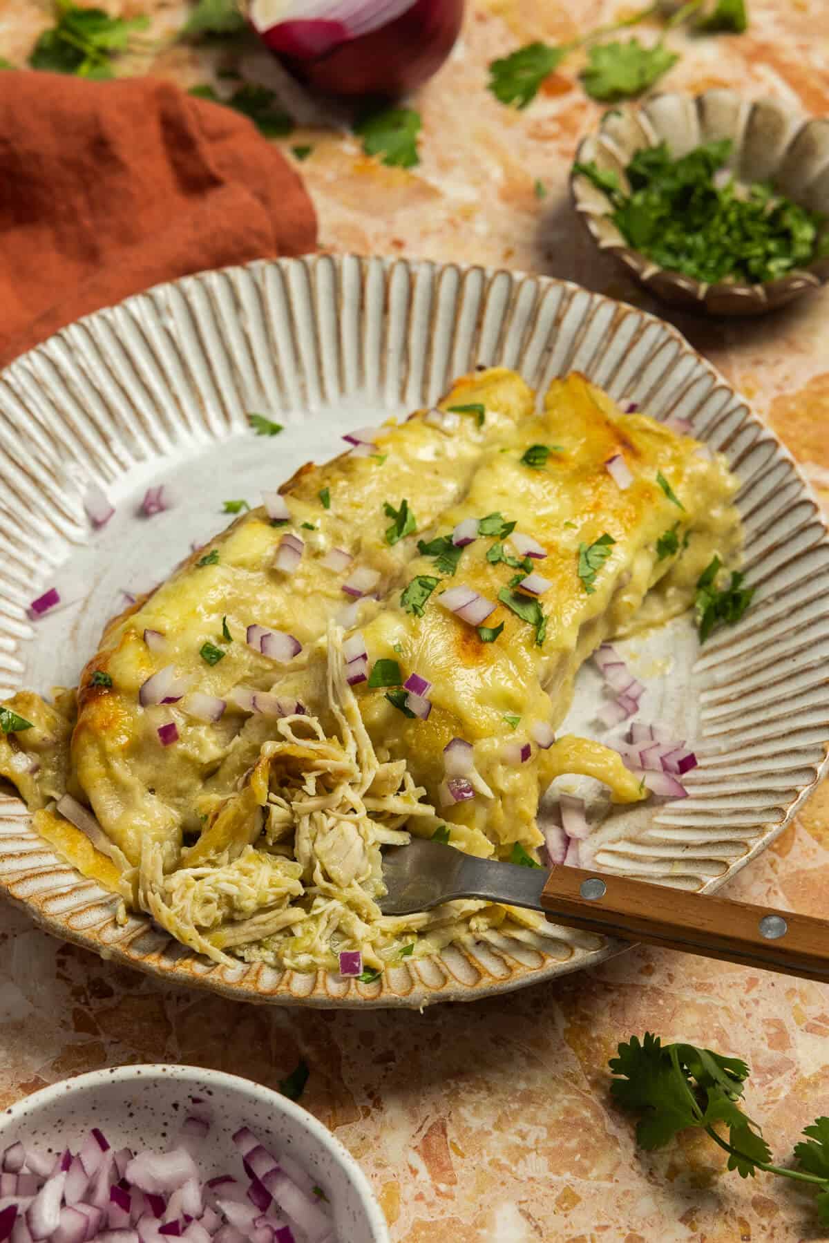 Two creamy chicken enchiladas on a plate.
