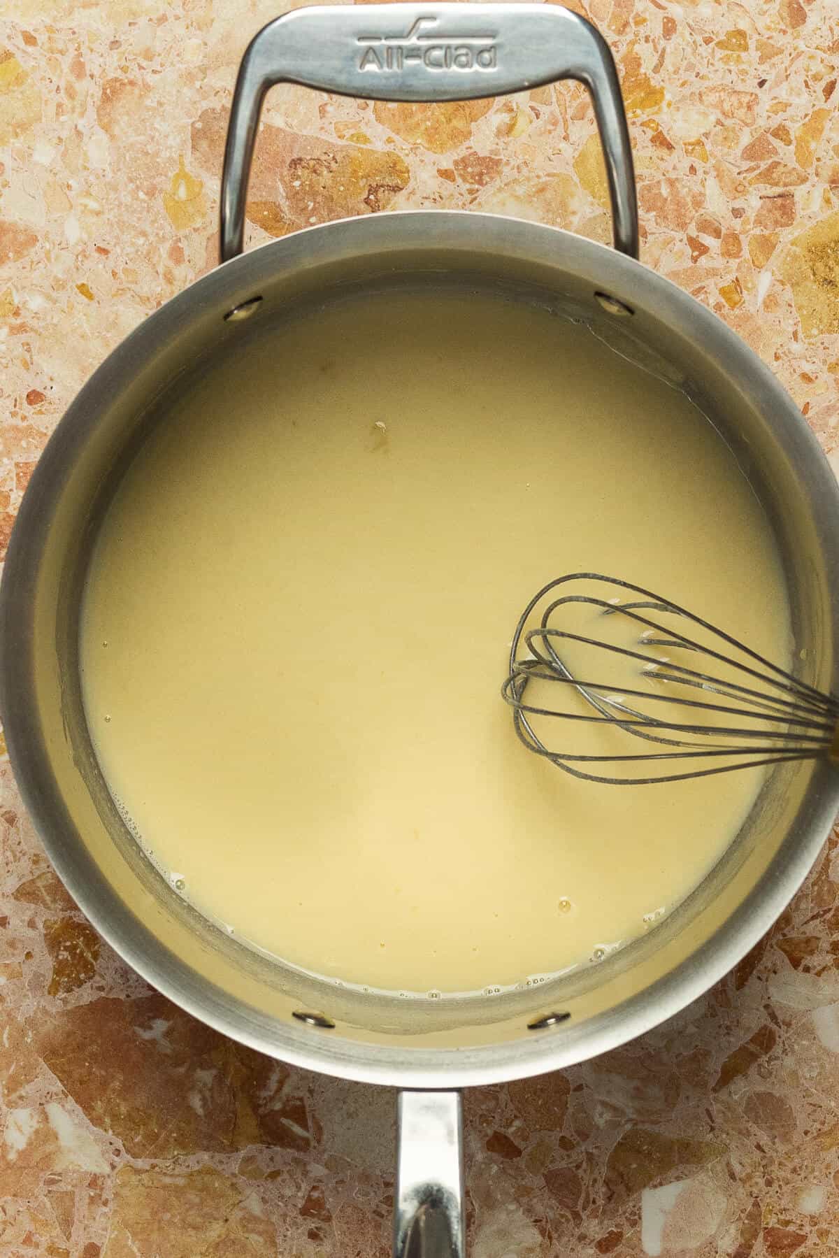 A large skillet with chicken broth added into a roux.