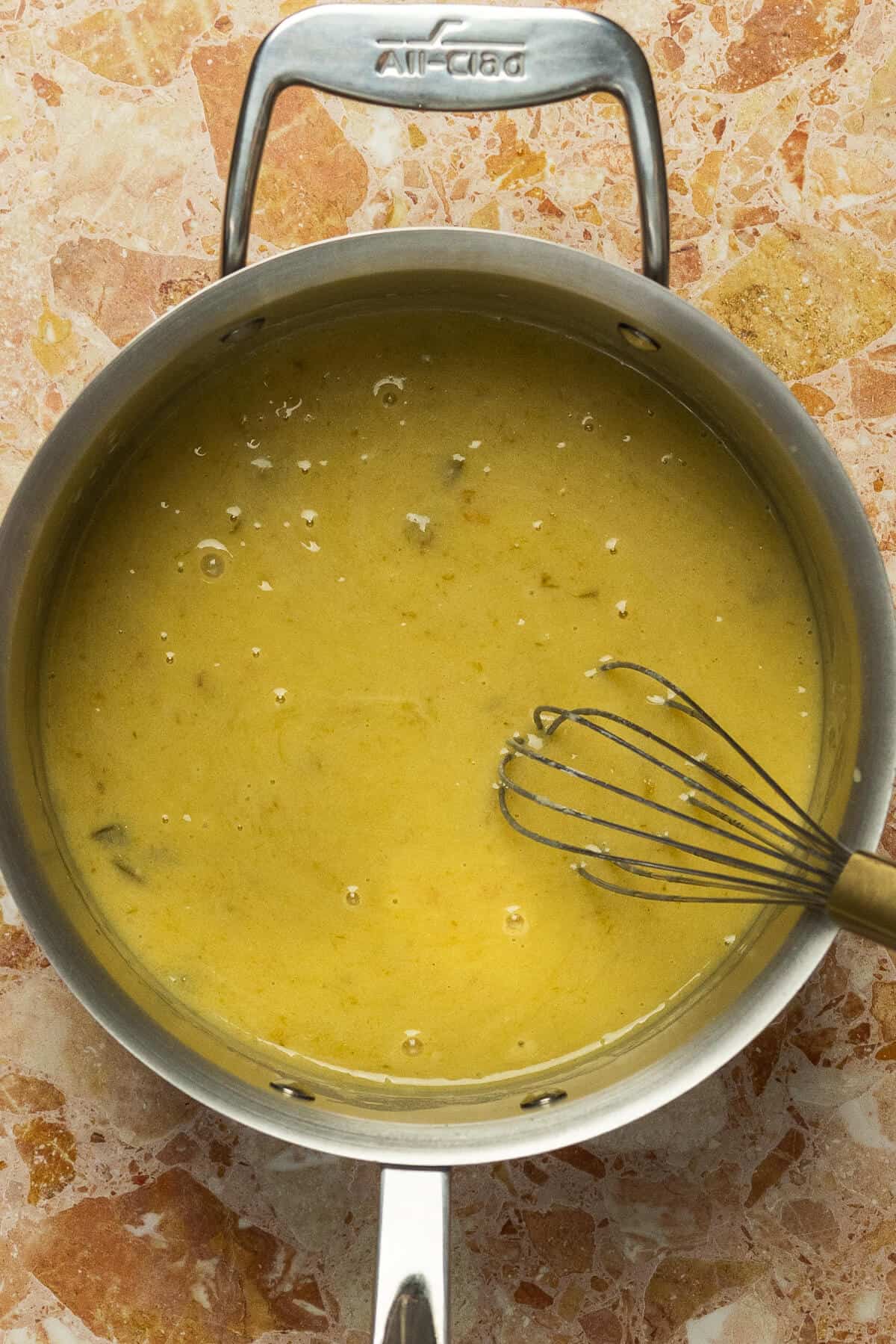 A large skillet with green enchilada sauce mixed into the roux mixture.