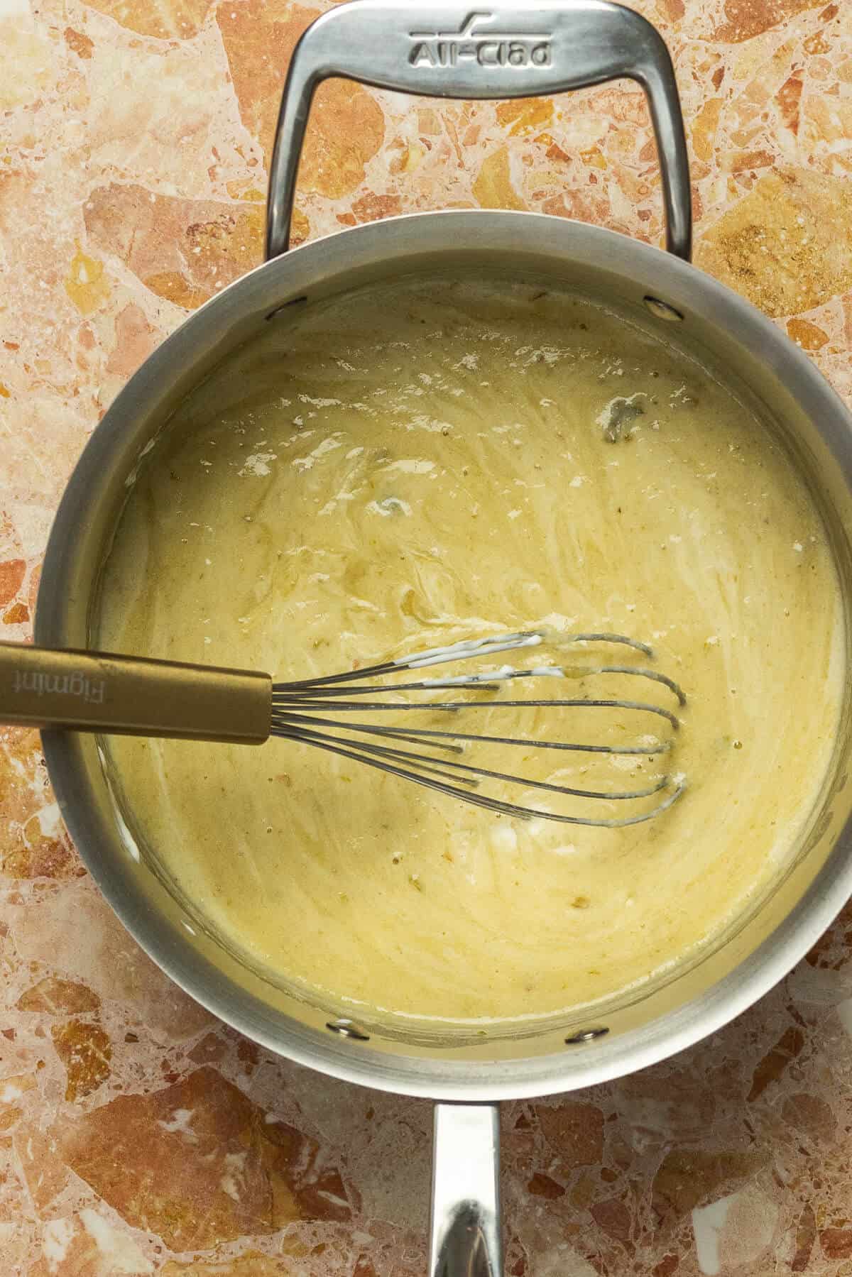 A large skillet with yogurt mixed into the green enchilada sauce mixture.