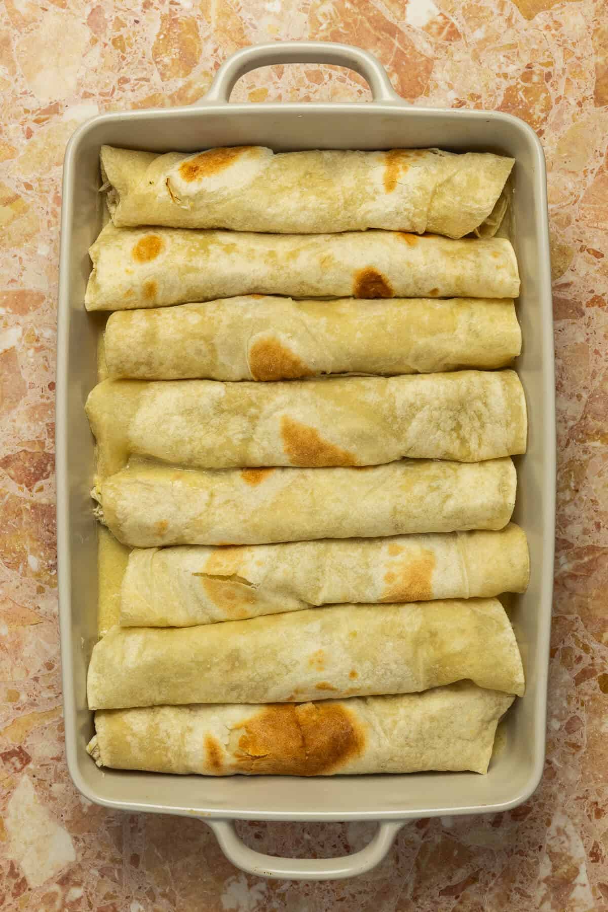 A 9x13 baking dish with 8 rolled enchiladas.